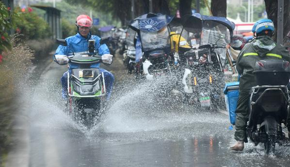 9日福州现明显降雨，市民骑车通过积水路段